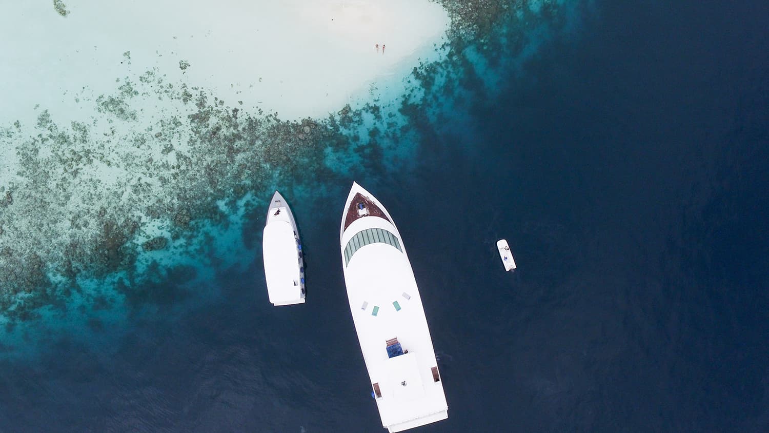 A yacht and a dinghy next to shore in the Maldives. 