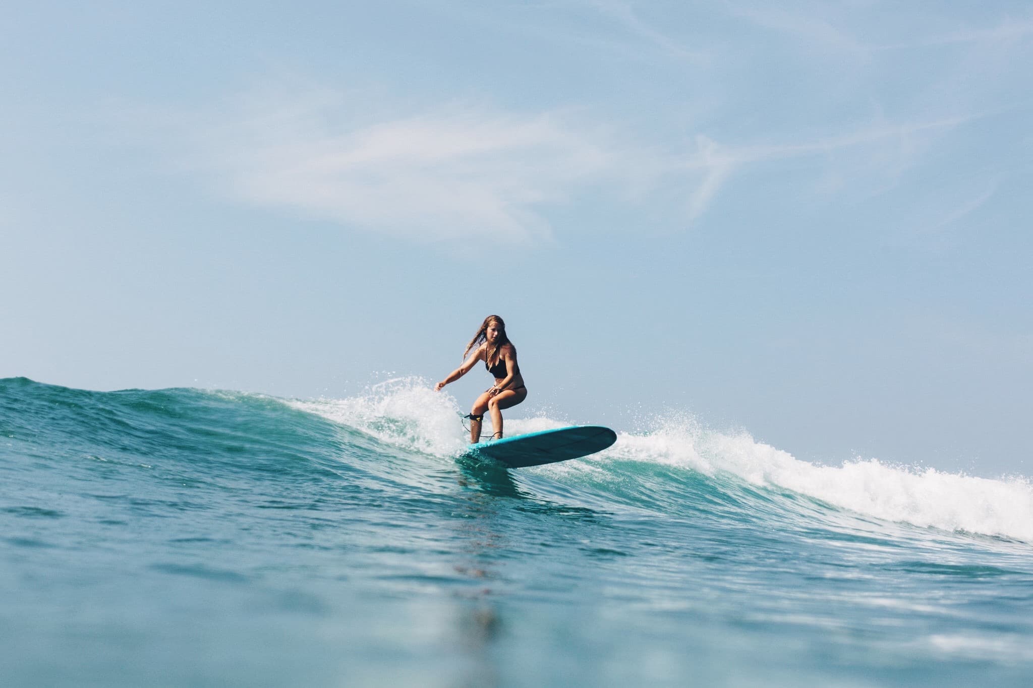 Girl surfing longboard waves in the Maldives