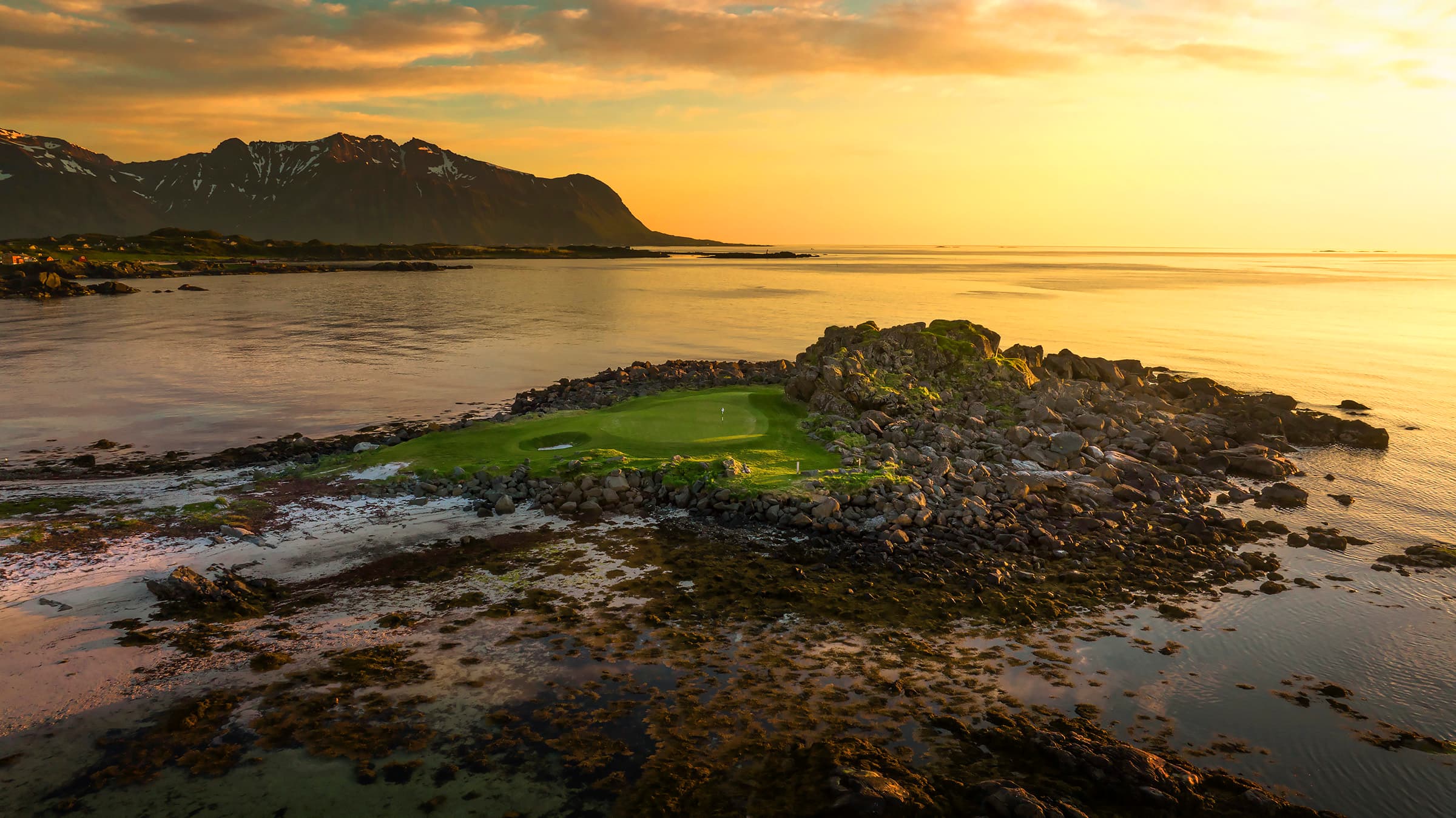 Golf green parked in the middle of the ocean in the Lofoten Links golf in Norway at sunset