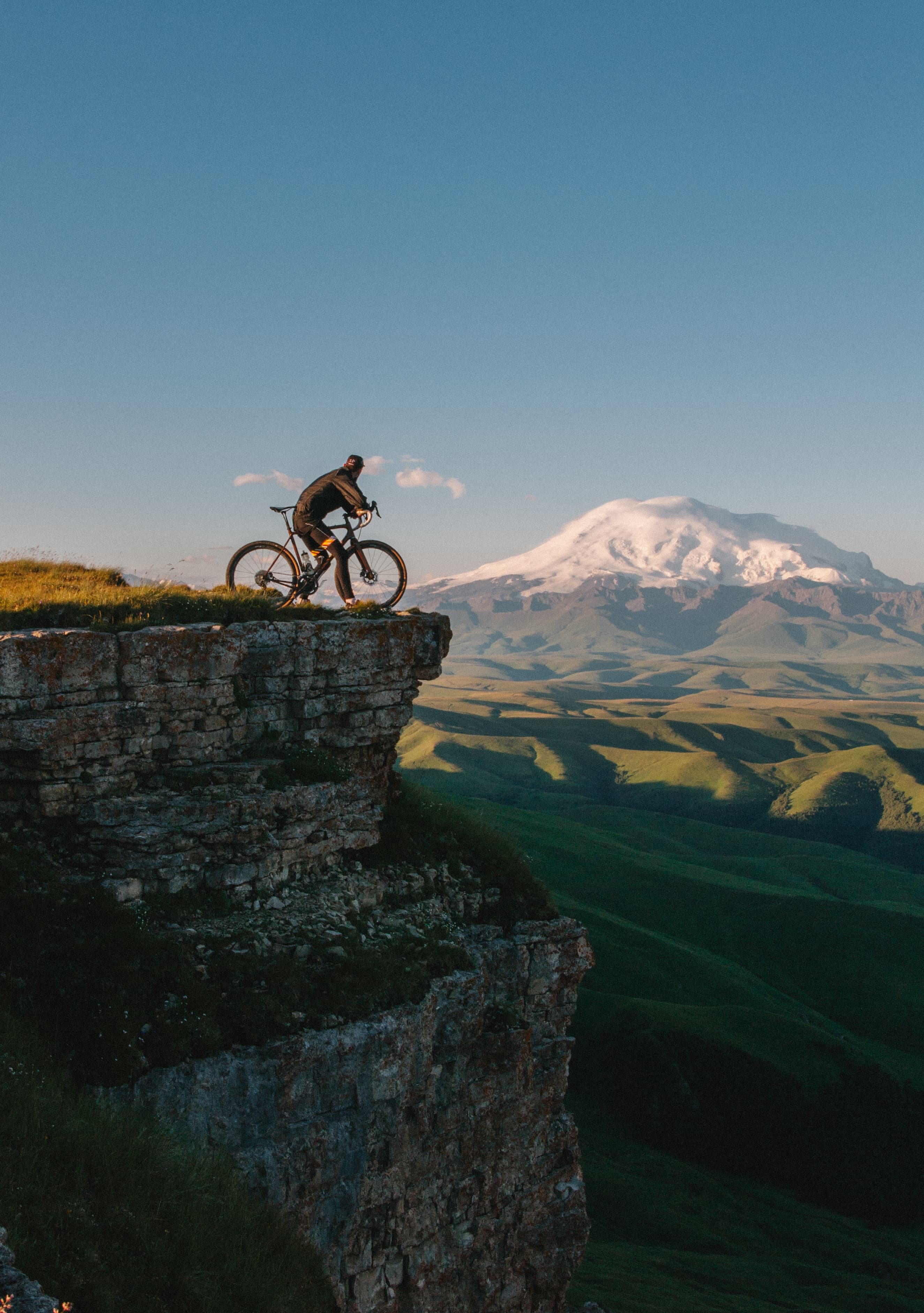 Guy on a bike overlooking snowy mountains