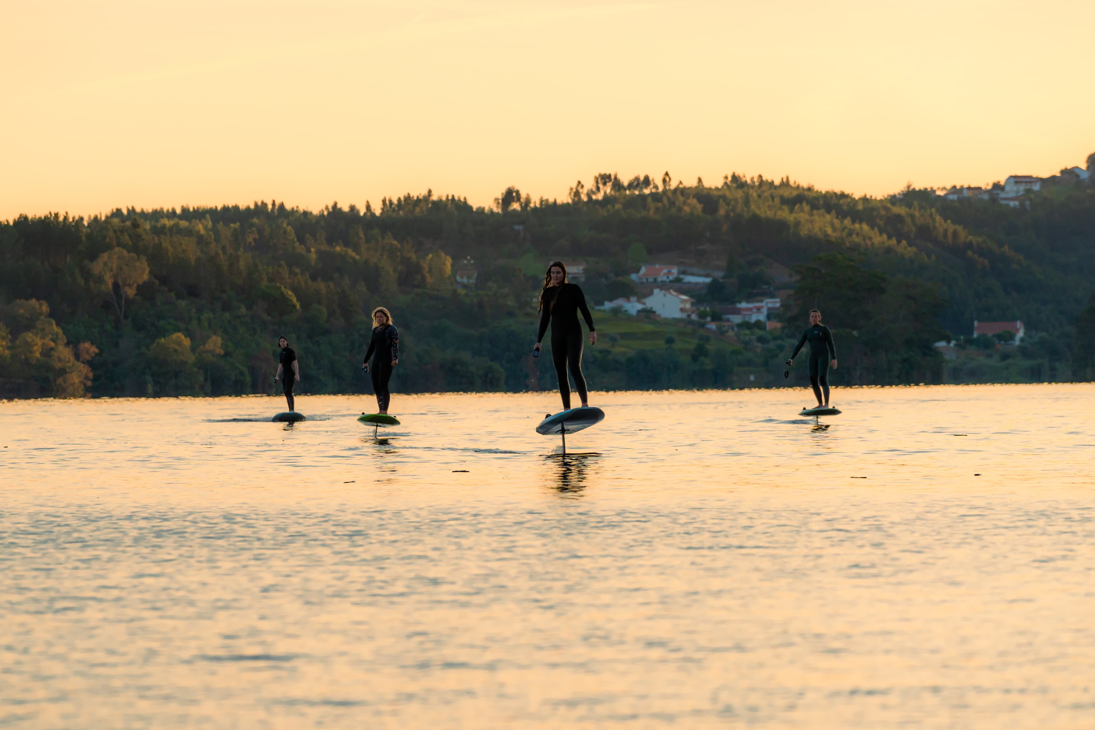 Group of friends efoiling in a lake in Portugal at sunset