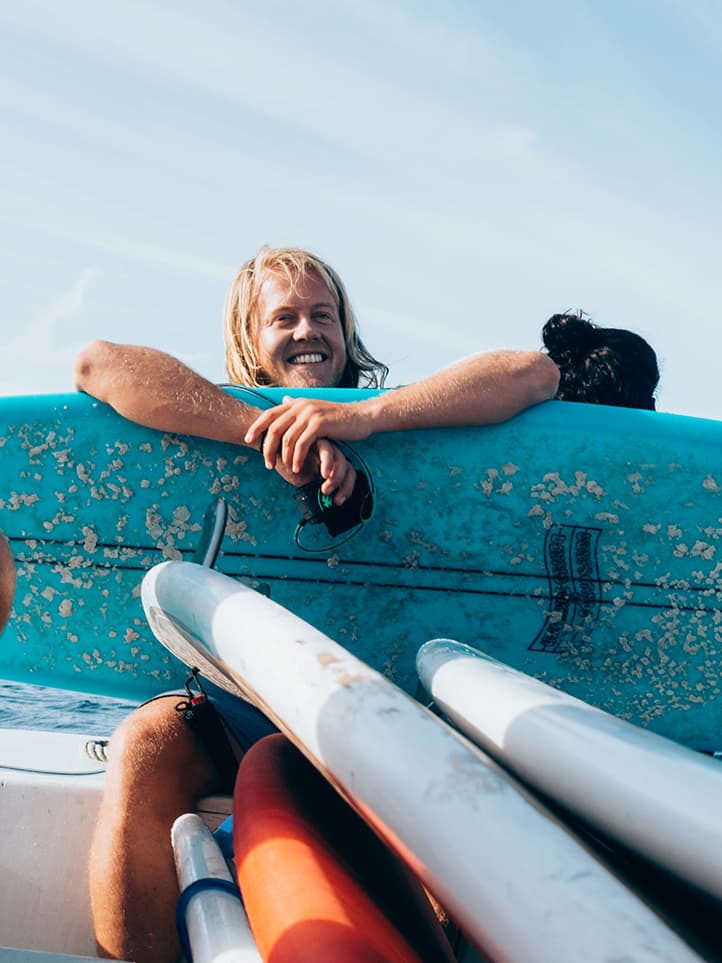 Man smiling with his surfboard in the Maldives