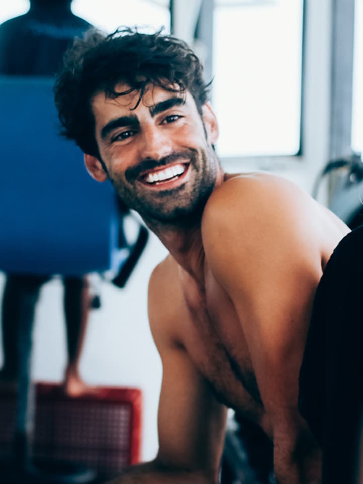 A guy smiles in a dinghy before going surfing.
