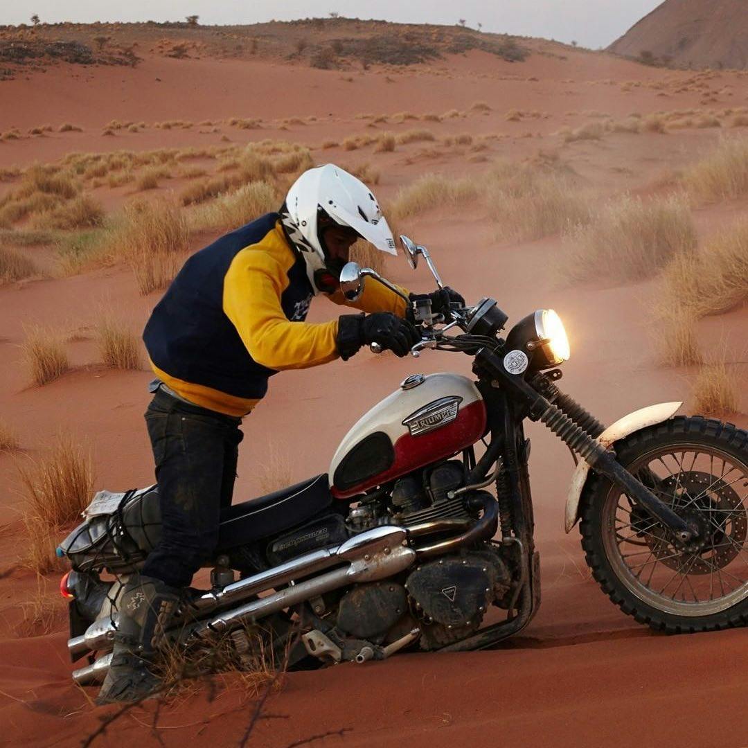 Biker trying to bring his motorbike out of the desert sands