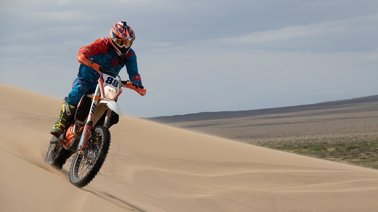 Guy riding an enduro bike in a desert dune