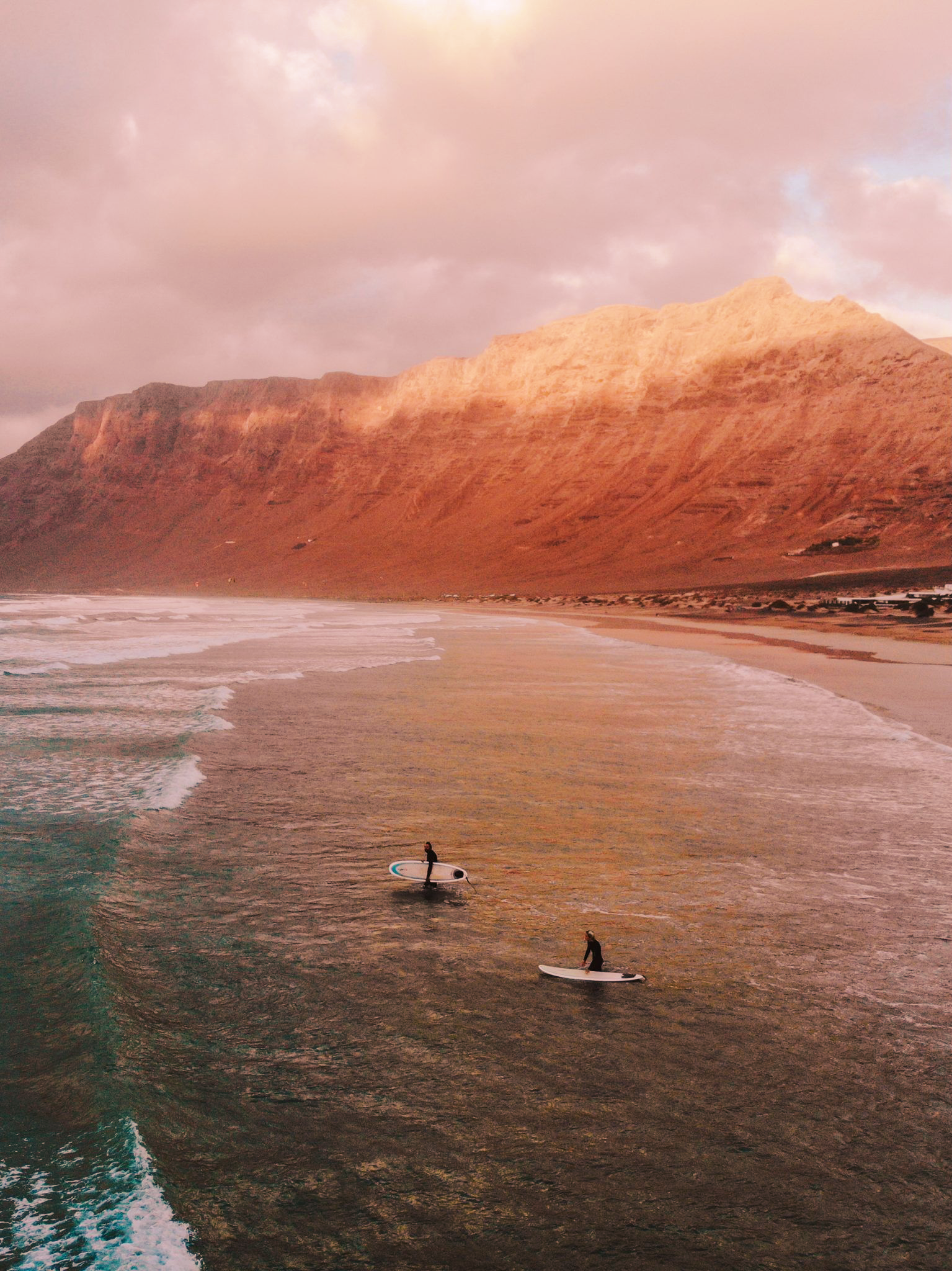 2 Surfers surging at sunset in the beach of Famara, Lanzarote