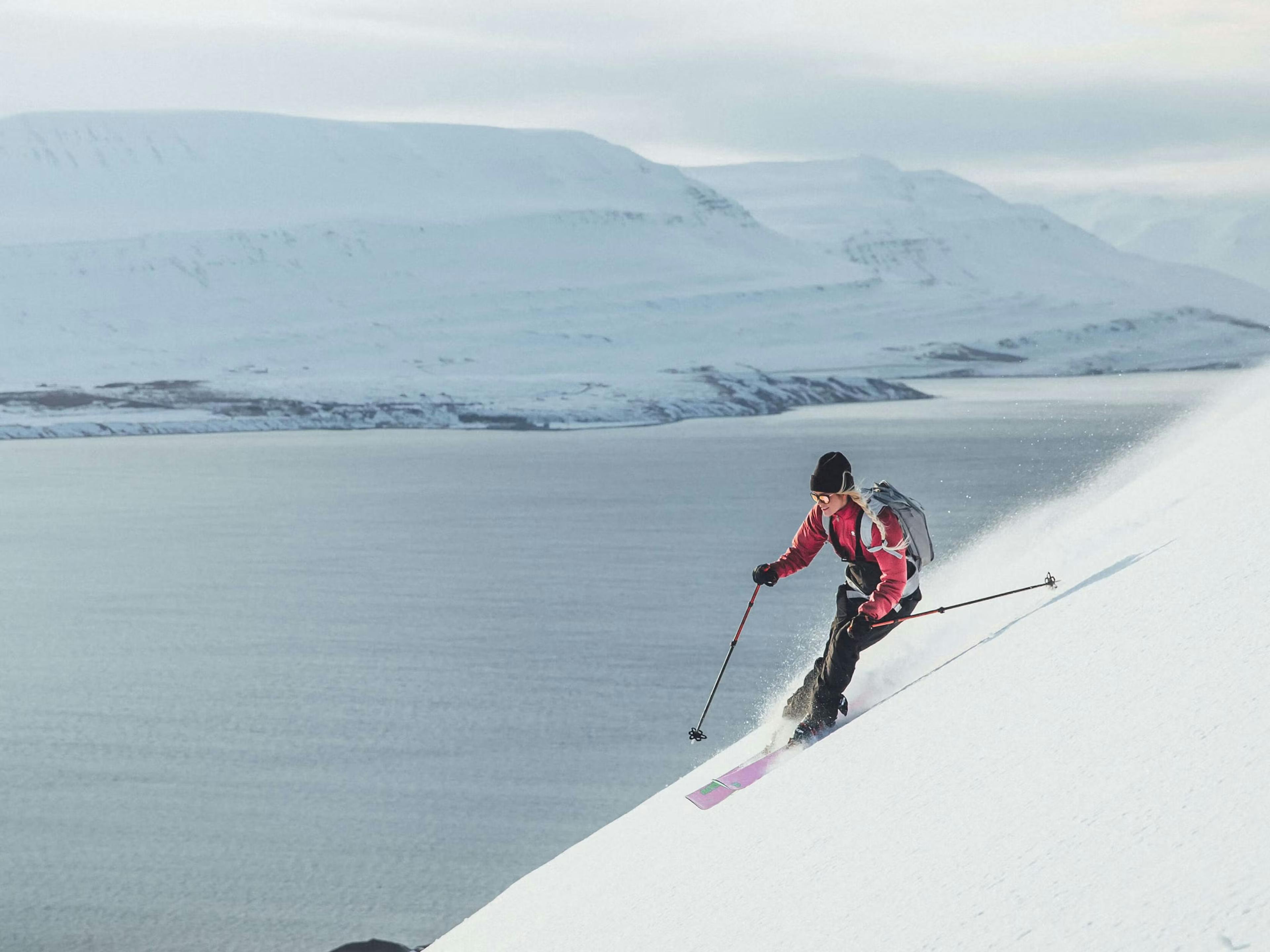 Girl skiing in iceland with ocean and snowed mountains in the background