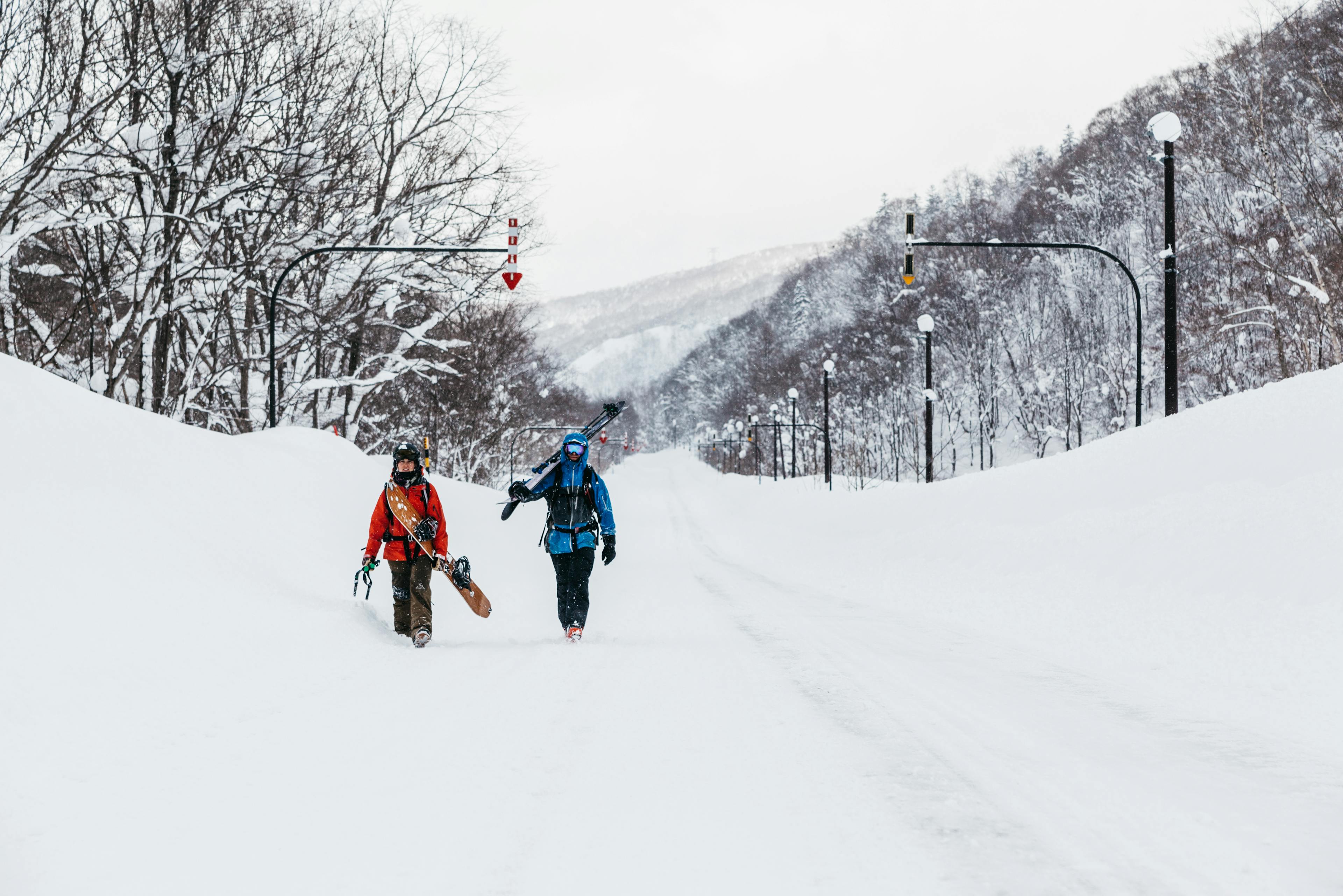 Snowboarder and skier walking in the snowy street of Niseko