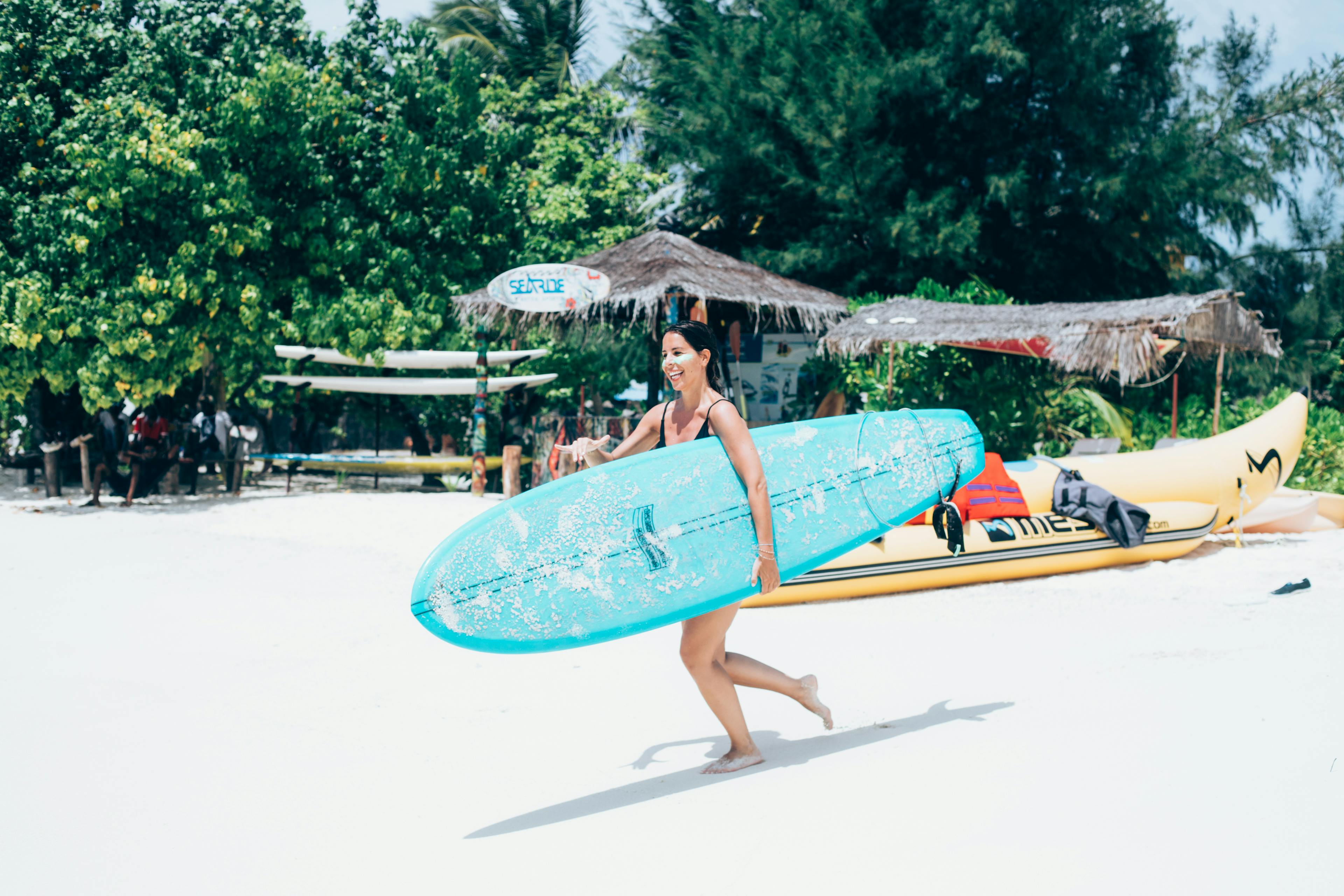 A girl runs to the beach with a surfboard in her hands.