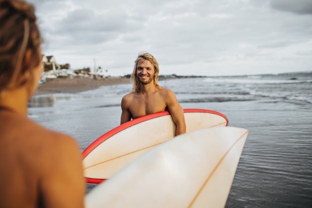 Smiling guy with surfboard under his arm in Bali