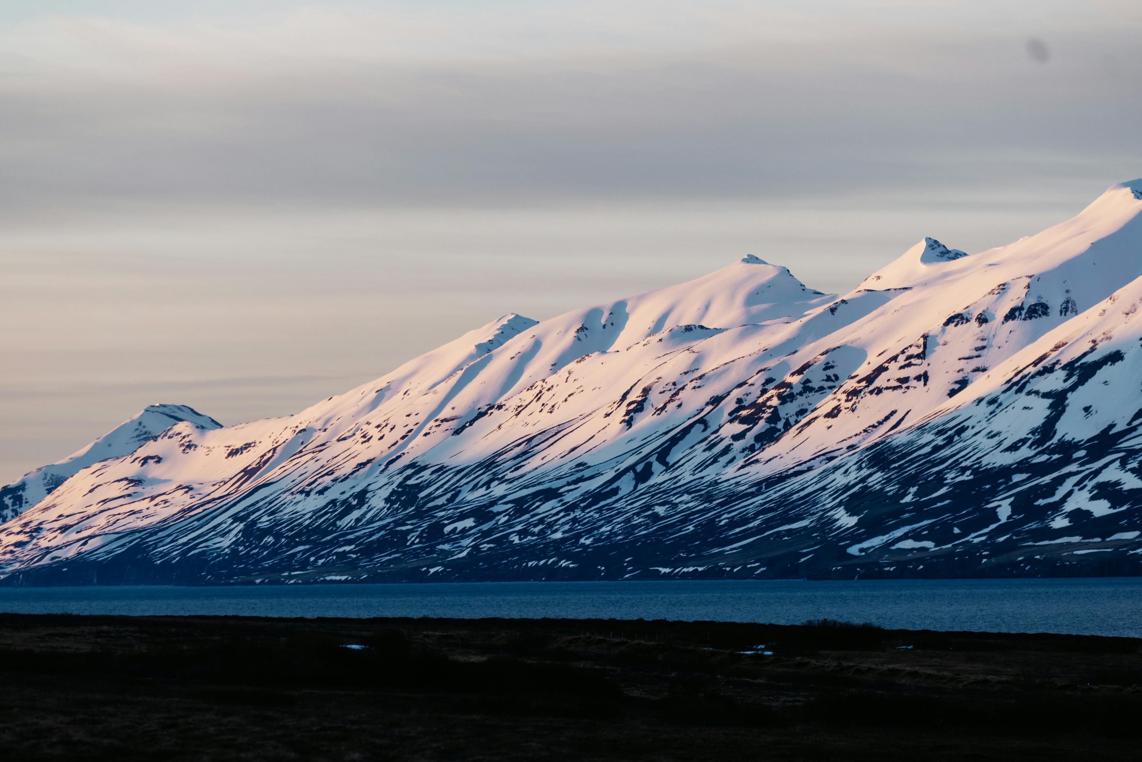 Mountains of Iceland at sunset with ocean and snow