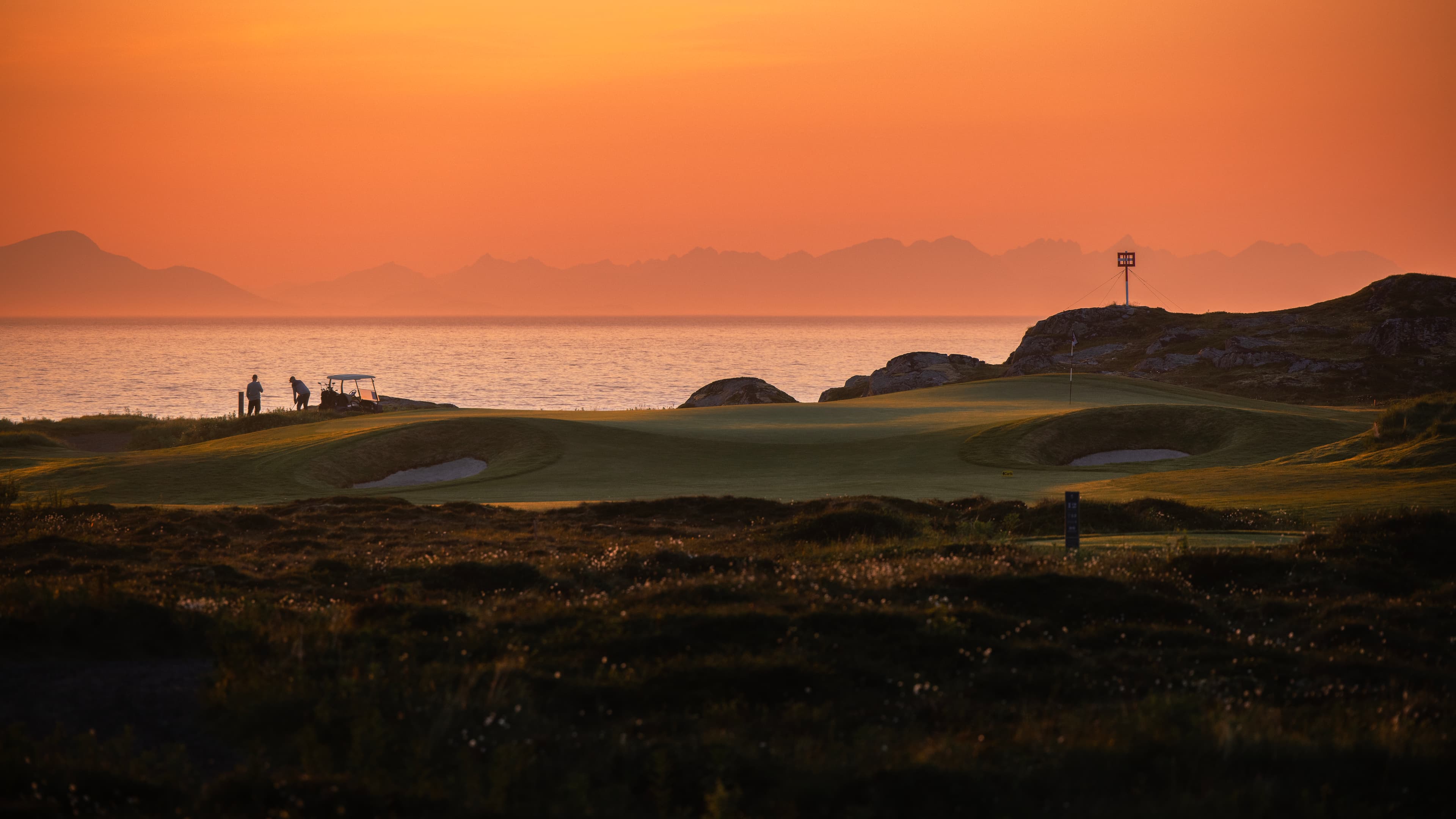 Friends playing golf at sunset in Lofoten Links, Norway